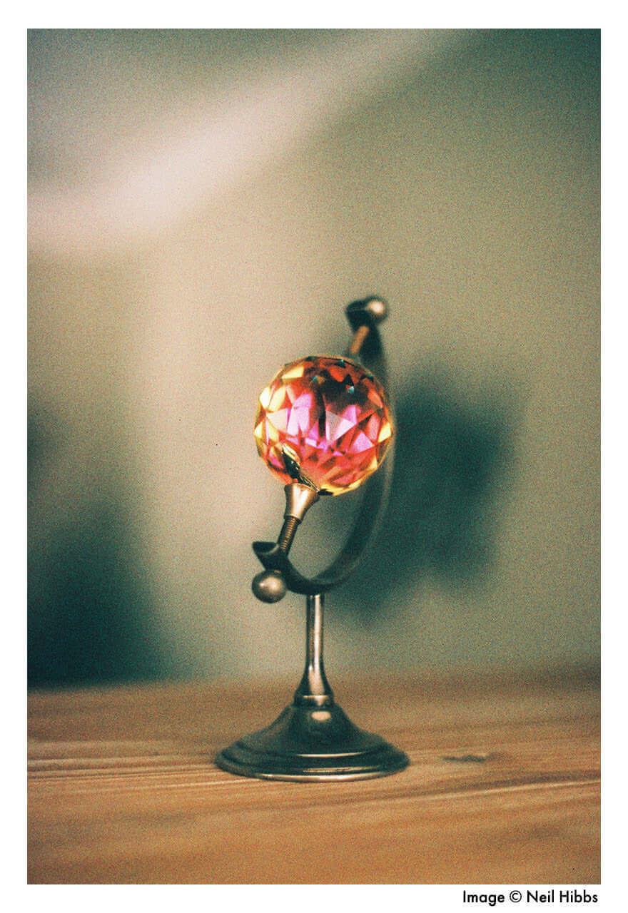 Artistic close-up of a decorative globe with a colorful crystal orb, set on a wooden surface.