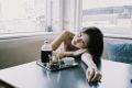 Young woman relaxing with a beverage on a table near a window, capturing a casual, serene moment.