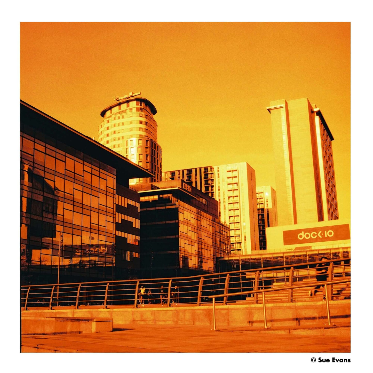 Orange-tinted urban landscape showcasing modern buildings and reflective glass, captured on HARMAN Redscale 120 film.