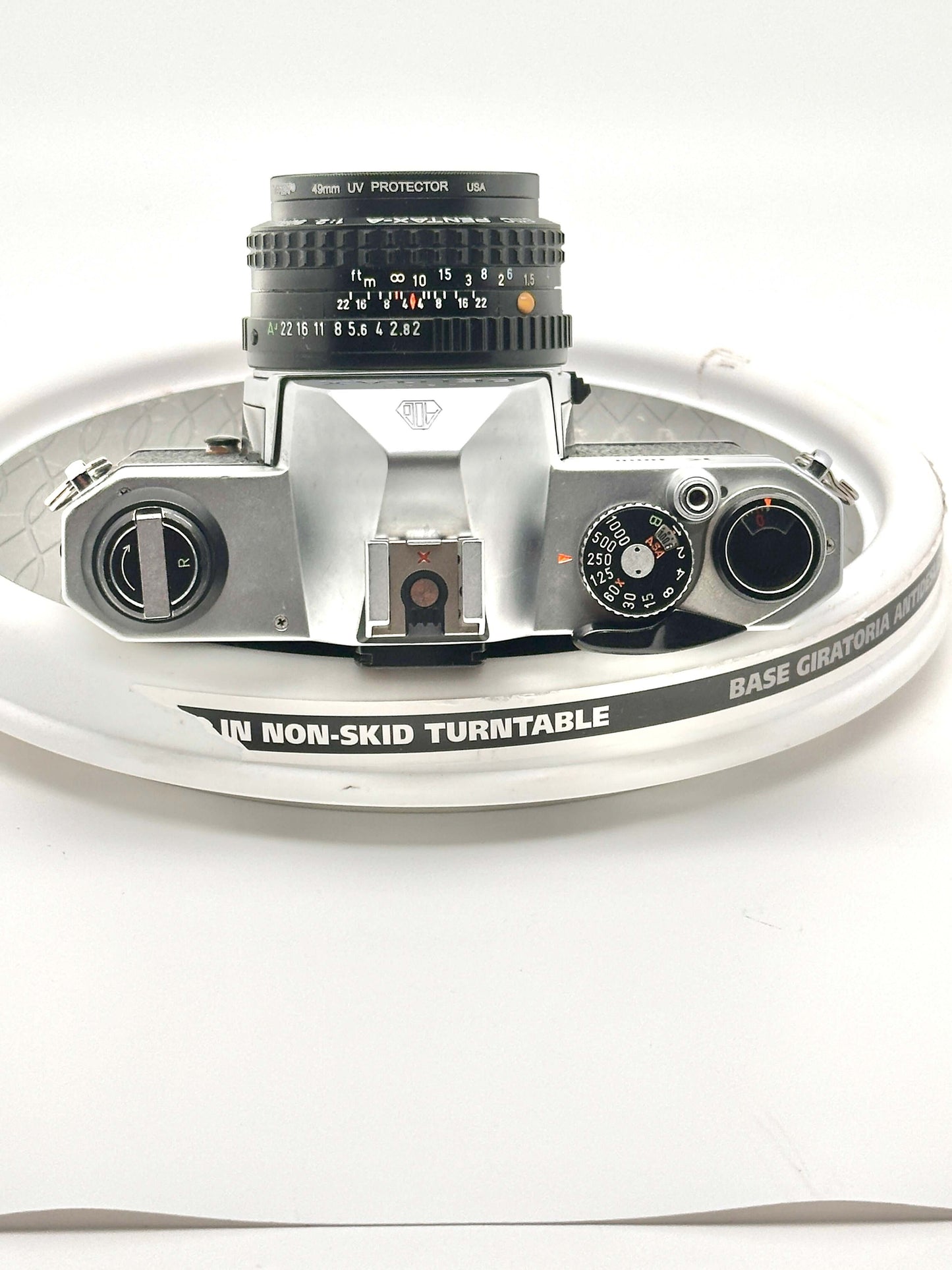 Top view of a silver Japanese Pentax K1000 35mm film camera with 50mm f2 lens on a non-skid turntable.