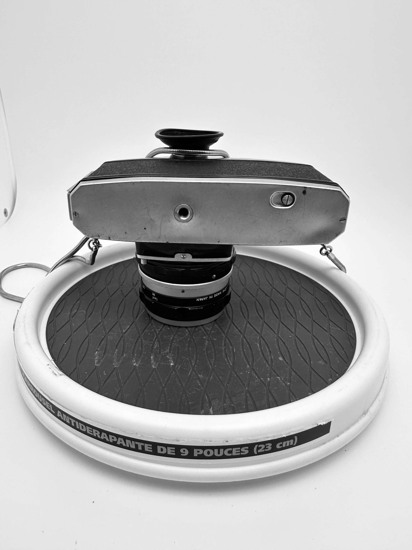 Nikkorex F 35mm film camera with 35mm f/2.8 lens on a display stand, showcasing vintage design and wear.