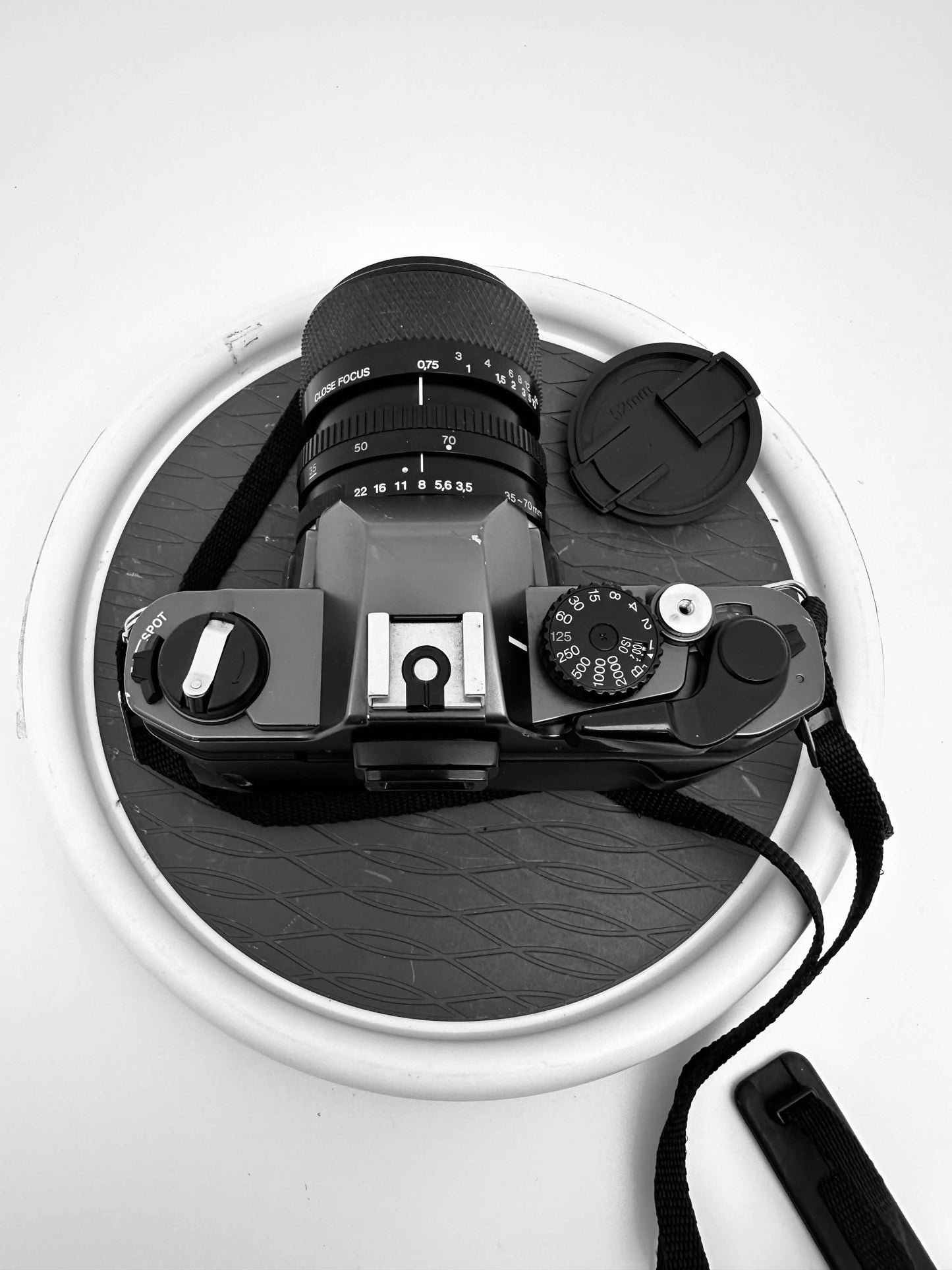 Olympus OM 2000 film camera with 35-70mm lens on a round backdrop, showcasing vintage design and manual controls.
