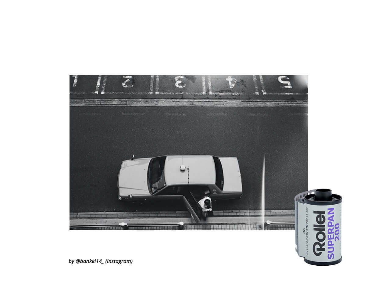 Black and white photo of a car parked on a city street next to a Rollei Superpan 200 film canister.