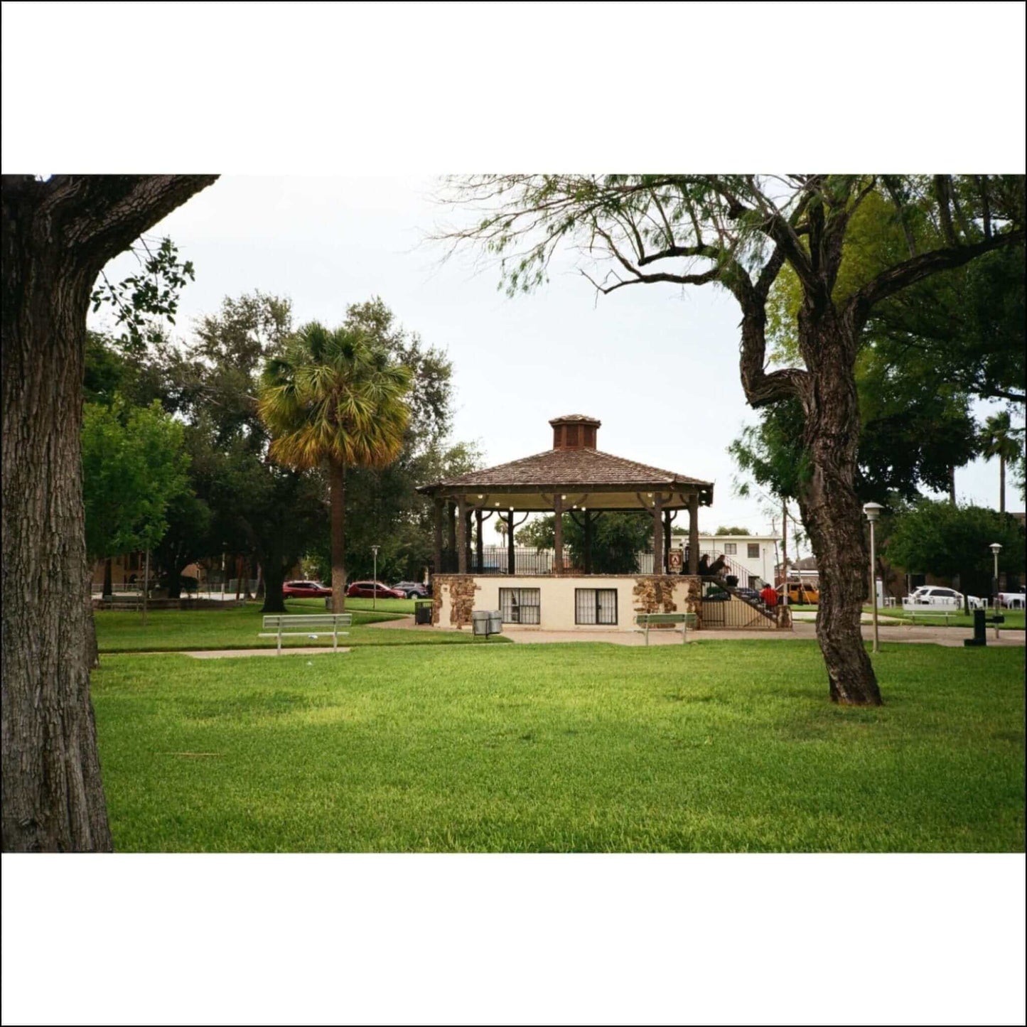 Scenic view of a gazebo in a park surrounded by trees and a grassy area.