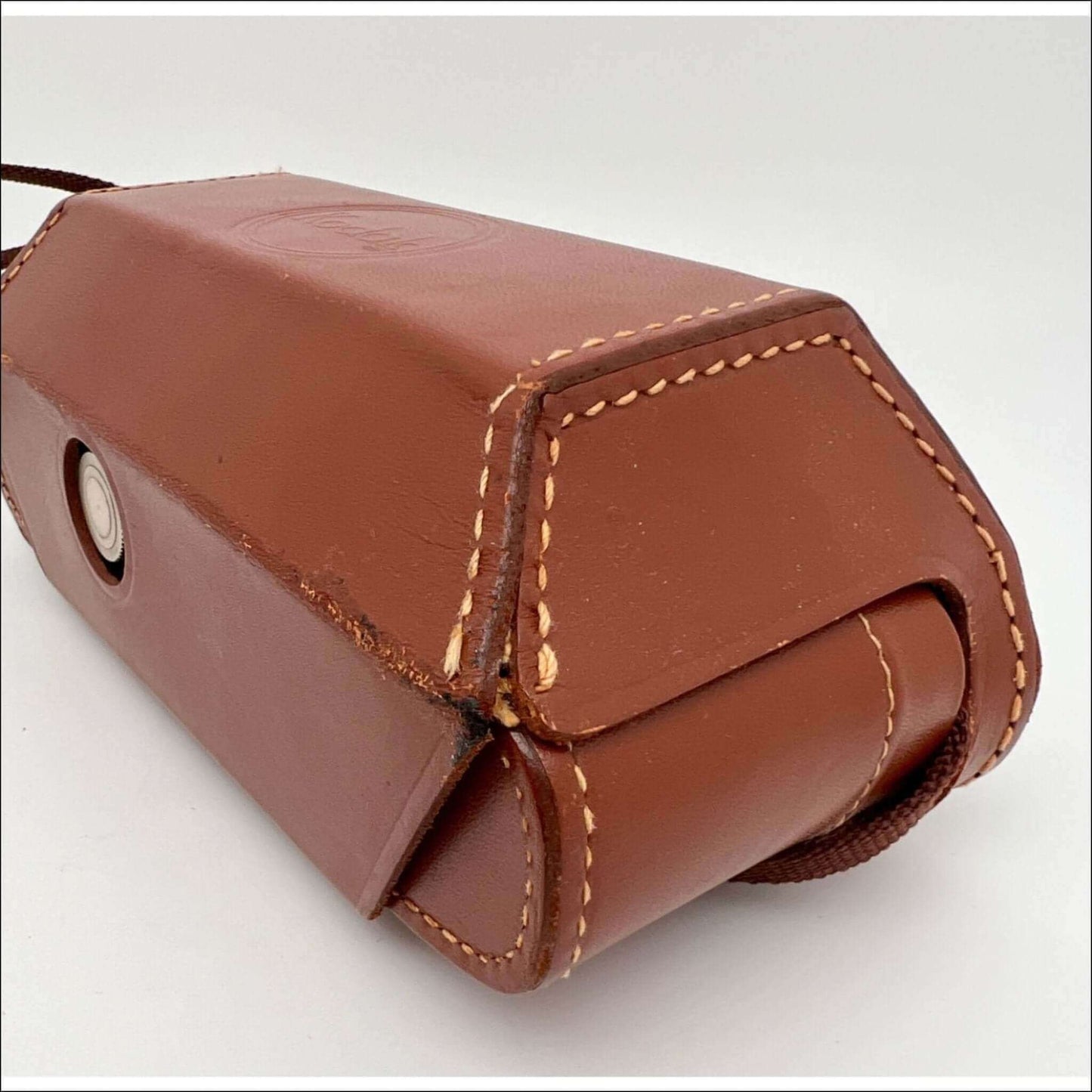 Close-up of a vintage Kodak film camera case showing worn leather and stitching detail.