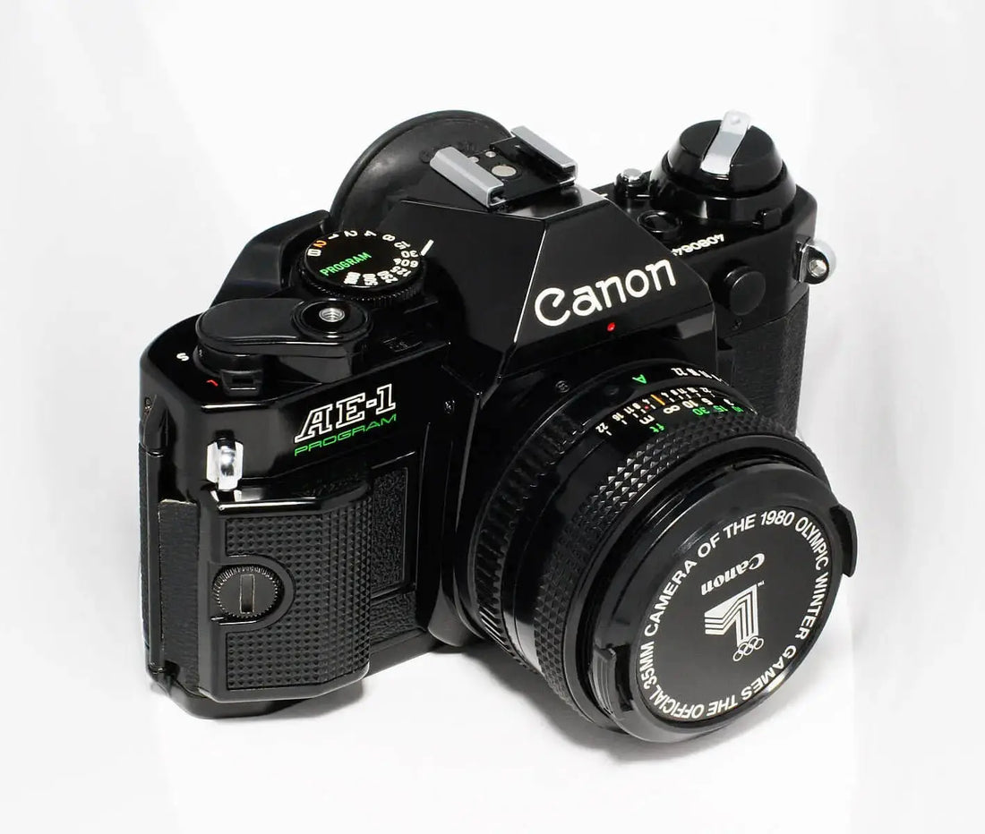 Black canon ae-1 program film camera with a matching lens cap featuring olympic branding.