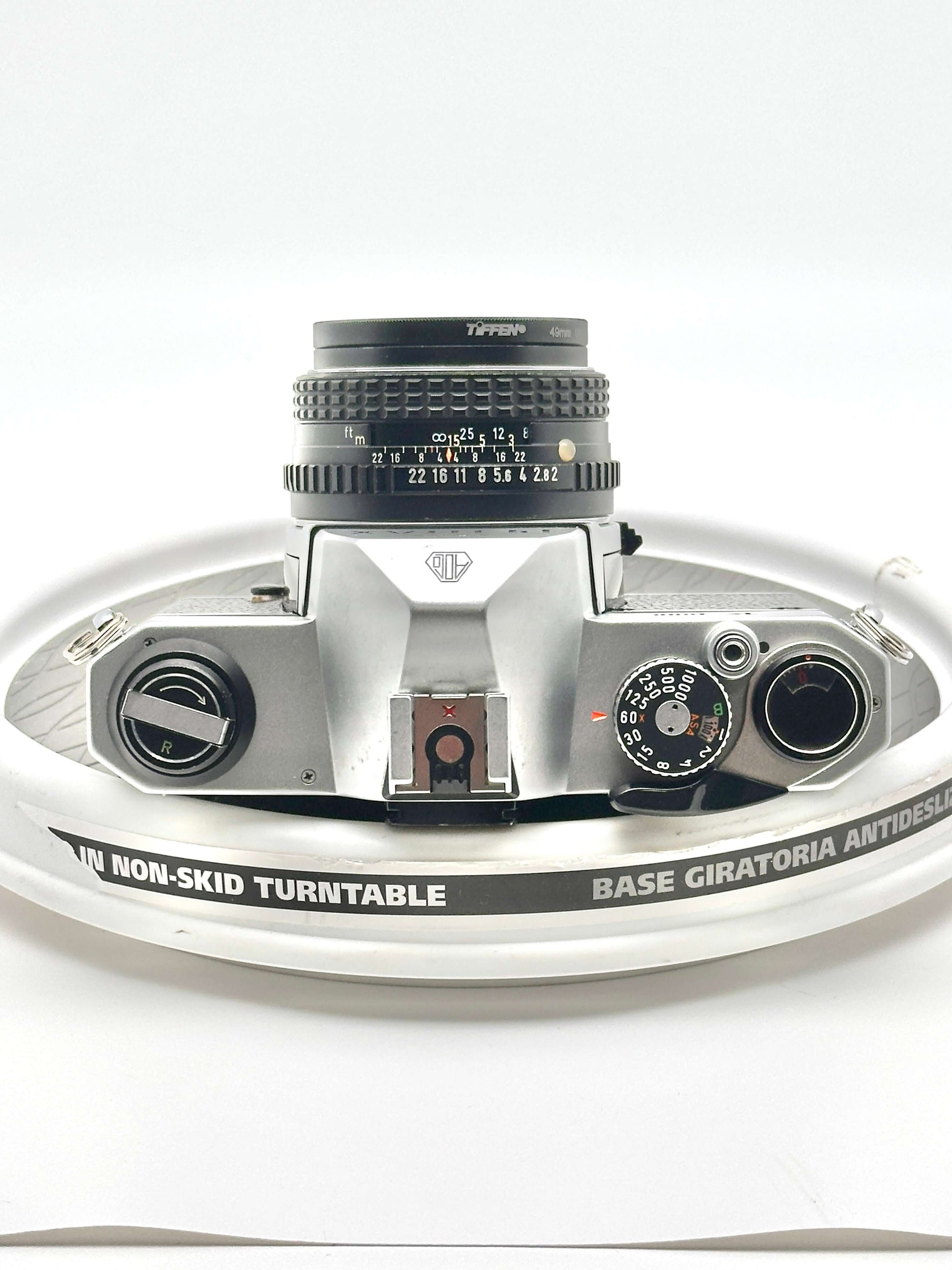 Close-up of a Pentax K1000 35mm film camera on a non-skid turntable, showcasing its lens and features.