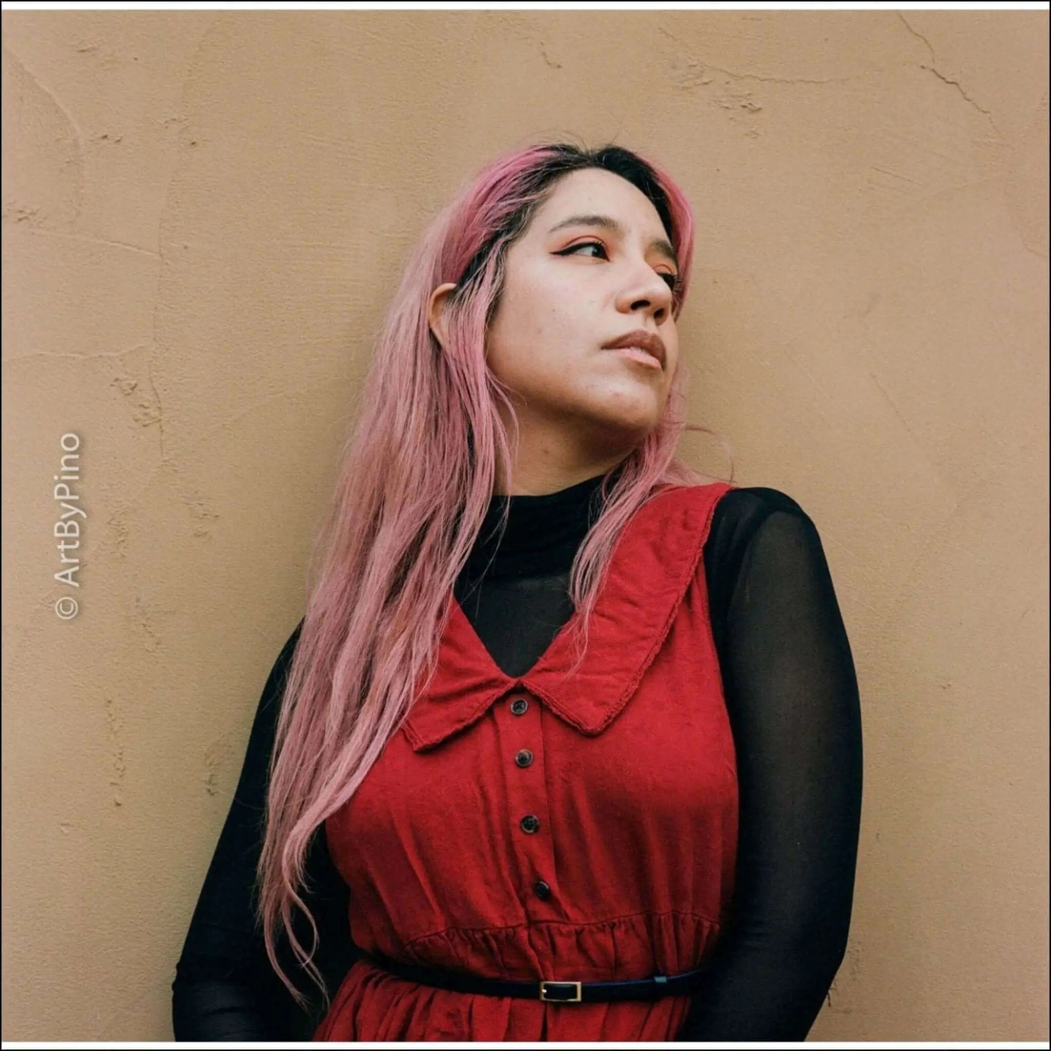 Red sleeveless dress with a collar and button front, worn over a black long-sleeved top