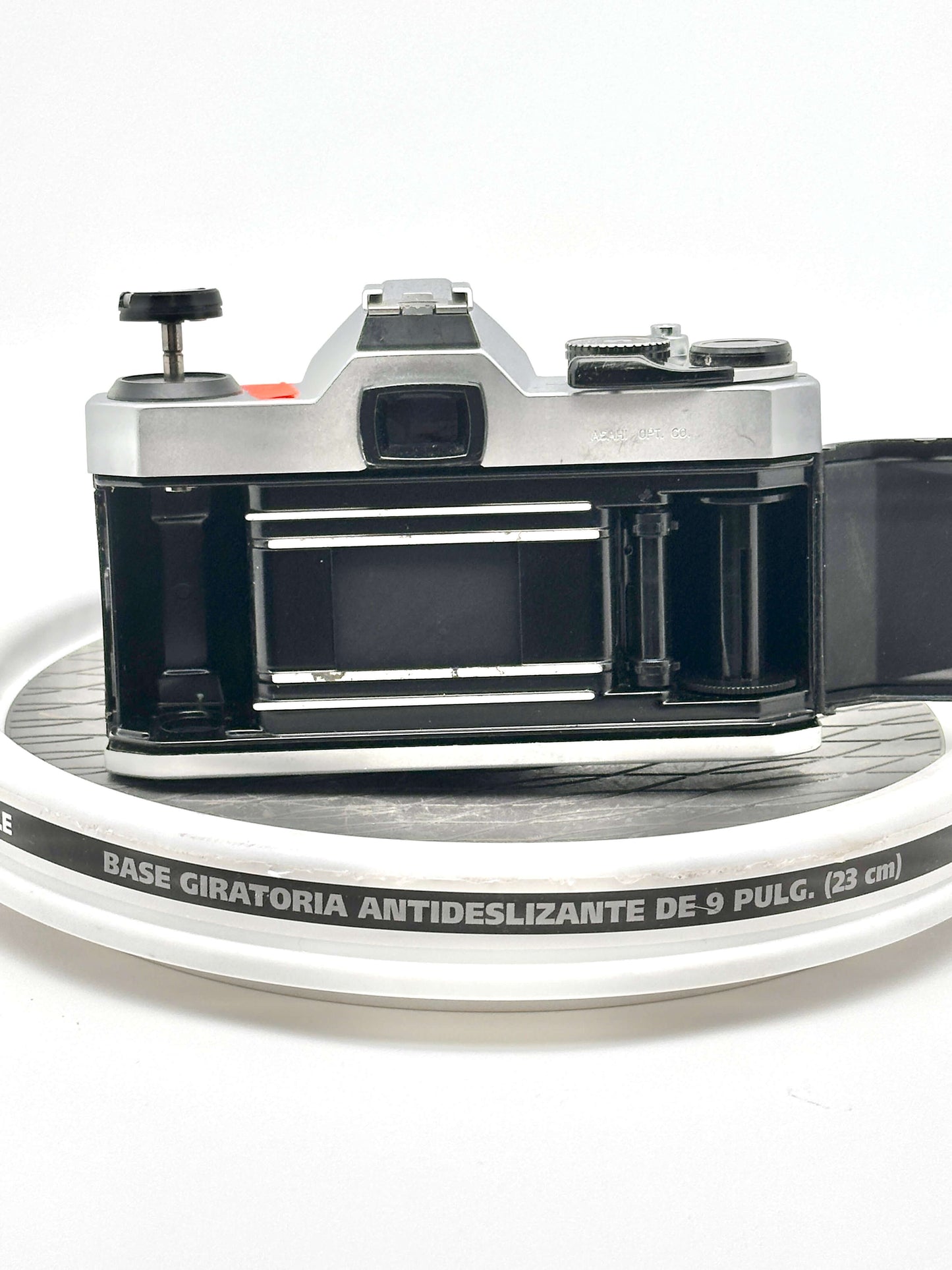 Pentax K1000 black 35mm film camera rear view on a round surface, showcasing its empty film compartment.