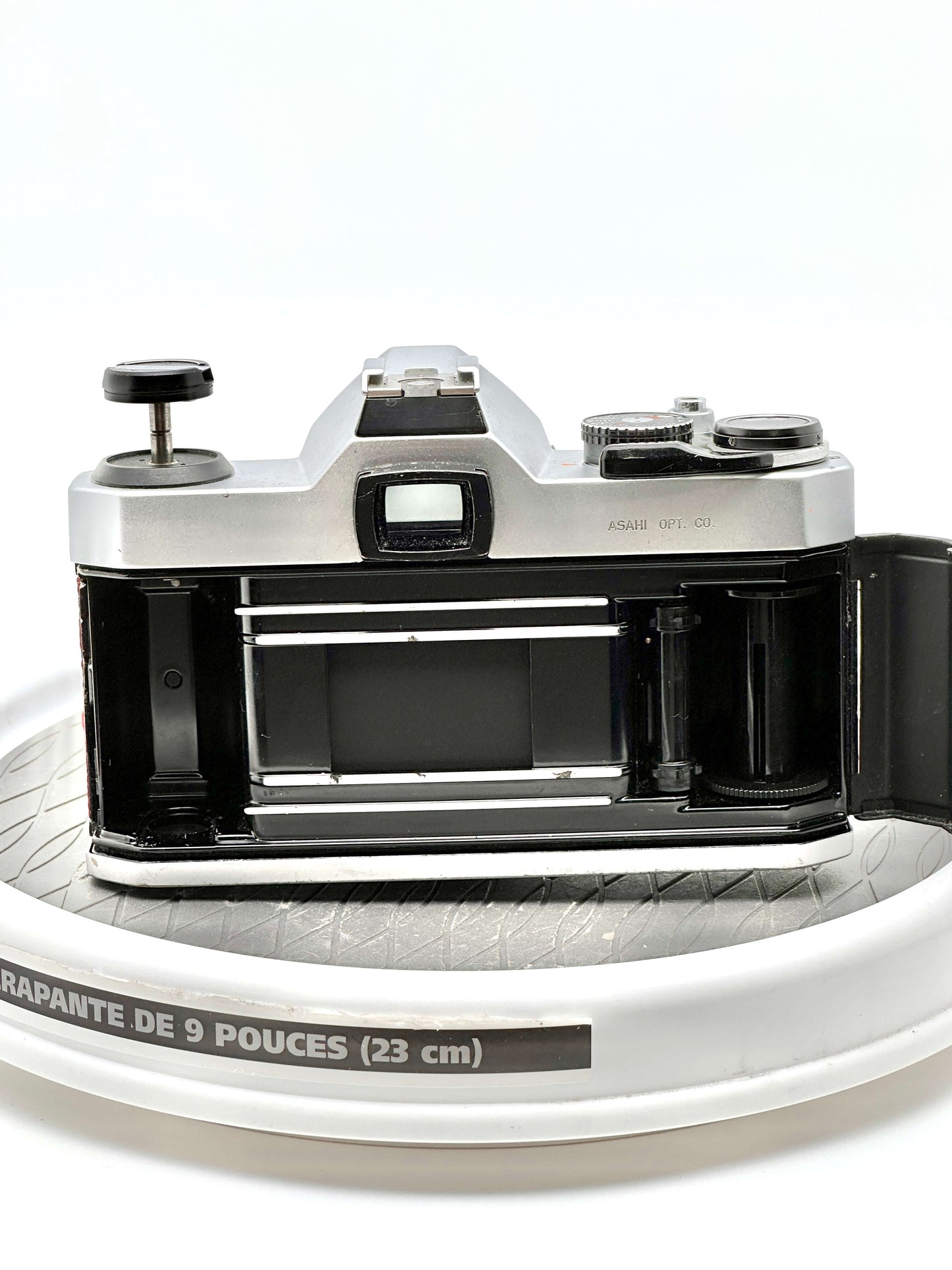 Pentax K1000 35mm film camera rear view showing the film compartment on a round surface.