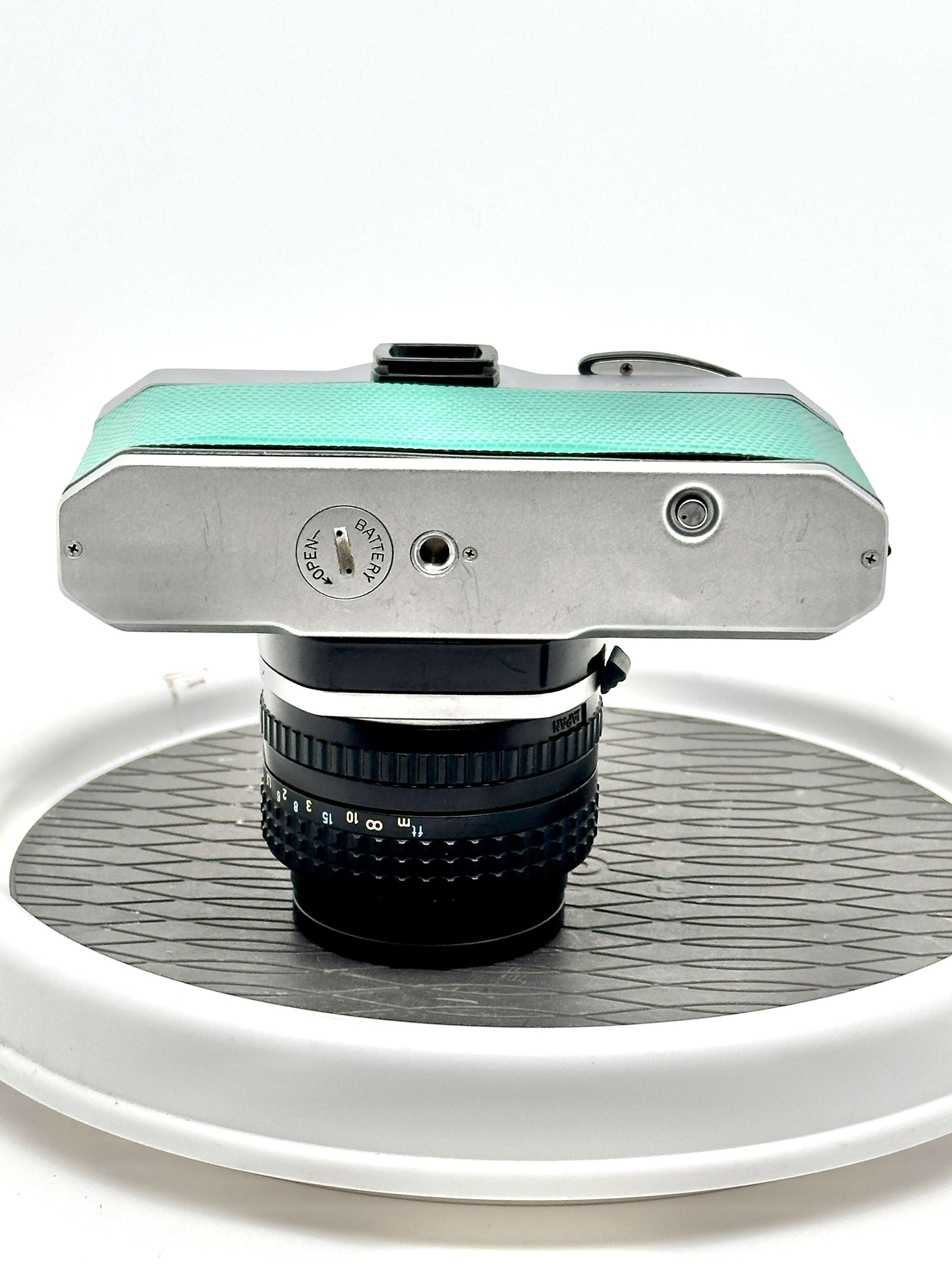 Top view of a teal Japanese Pentax K1000 35mm film camera with 50mm f1.4 lens, showcasing its vintage design.