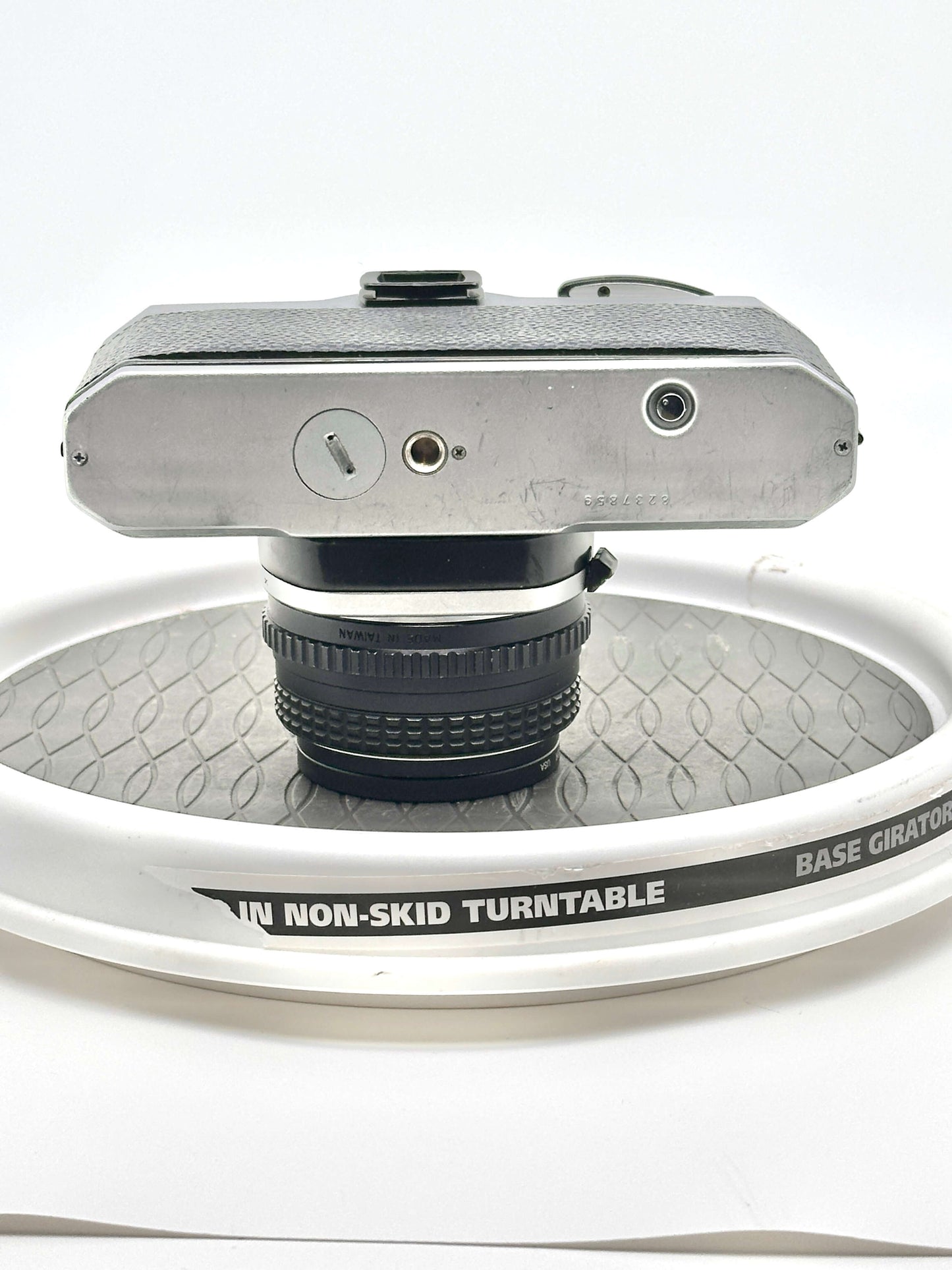 Top view of a Japanese Pentax K1000 camera mounted on a non-skid turntable showcasing its design and lens.