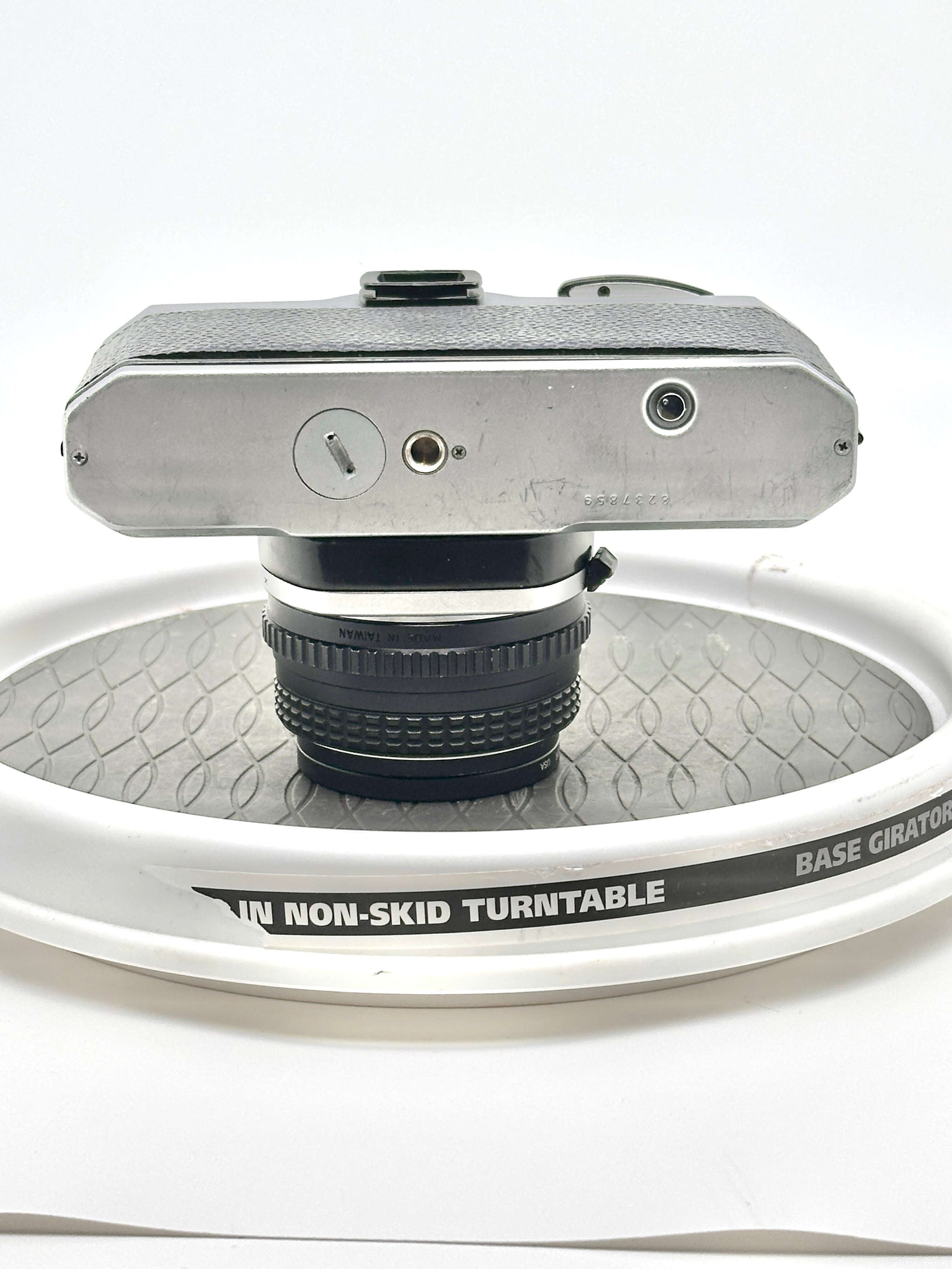 Top view of a Japanese Pentax K1000 camera mounted on a non-skid turntable showcasing its design and lens.