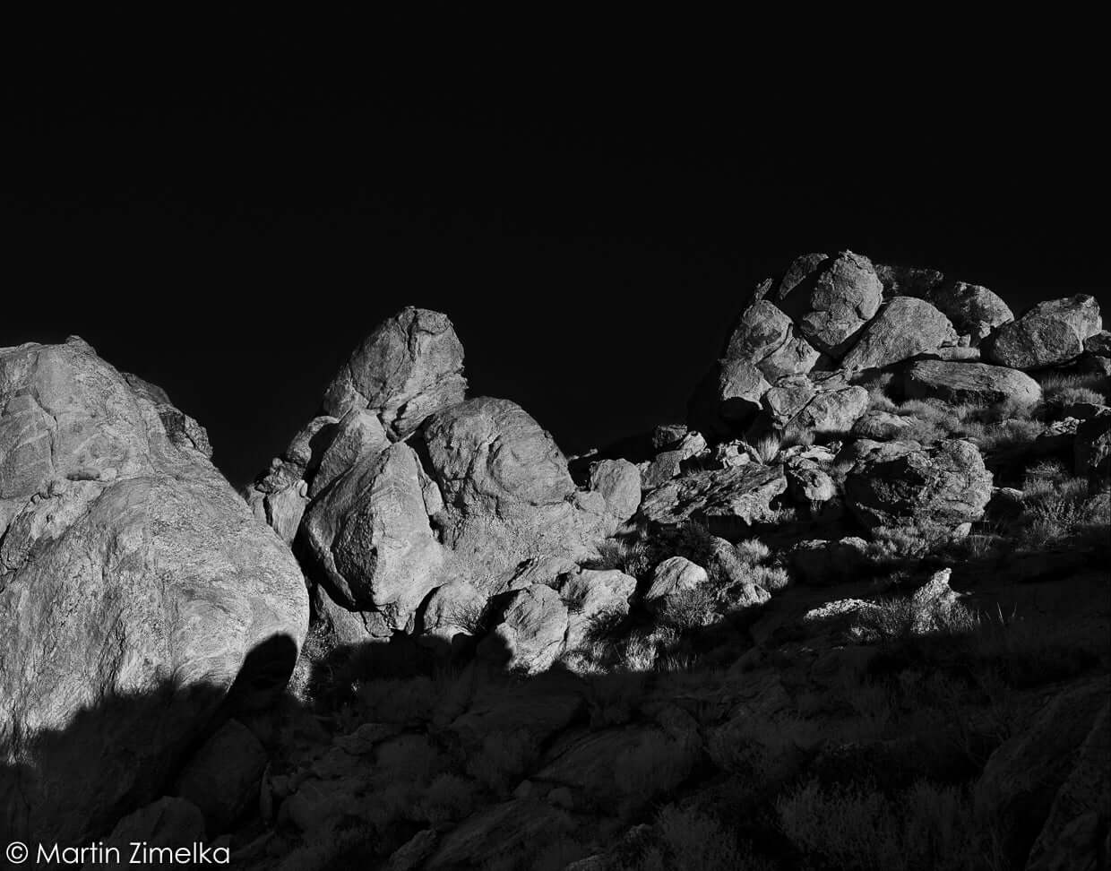Black and white image of rugged rock formations under dramatic lighting.