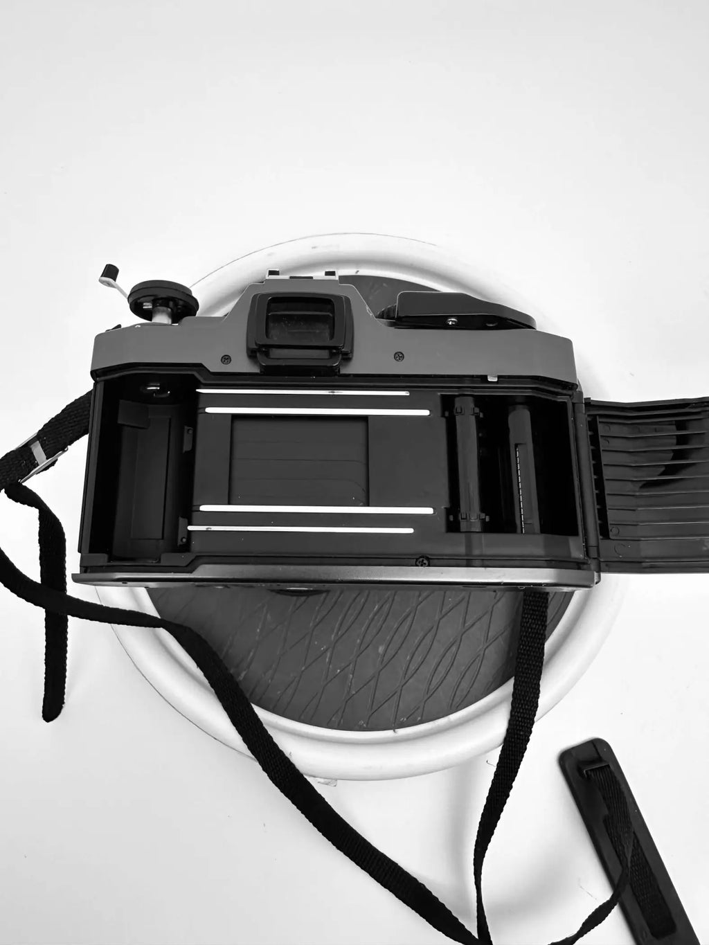 Black plastic-bodied film camera with a visible shutter mechanism and attached strap.