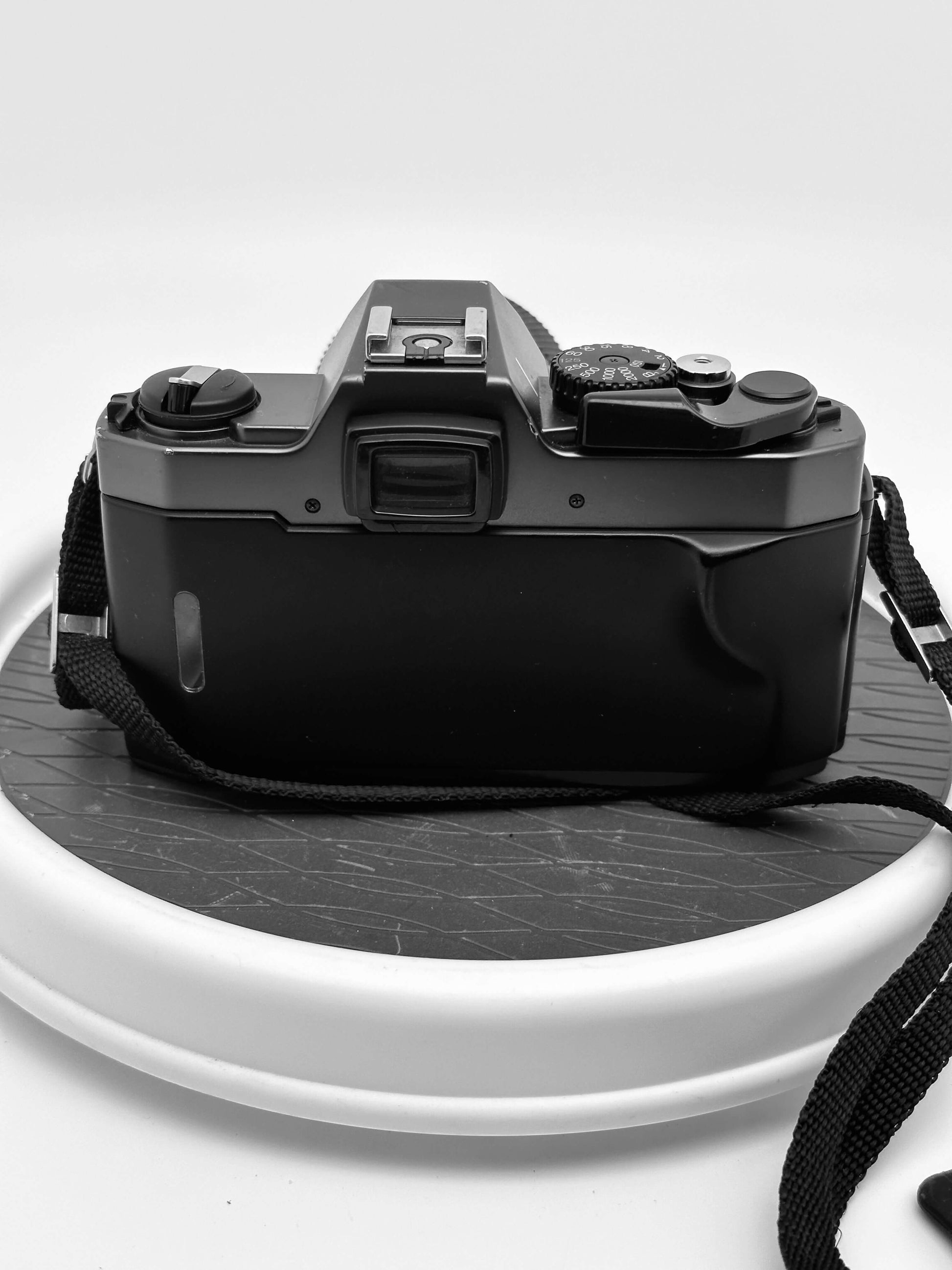 Back view of Olympus OM 2000 film camera on a rotating display, showcasing vintage design.