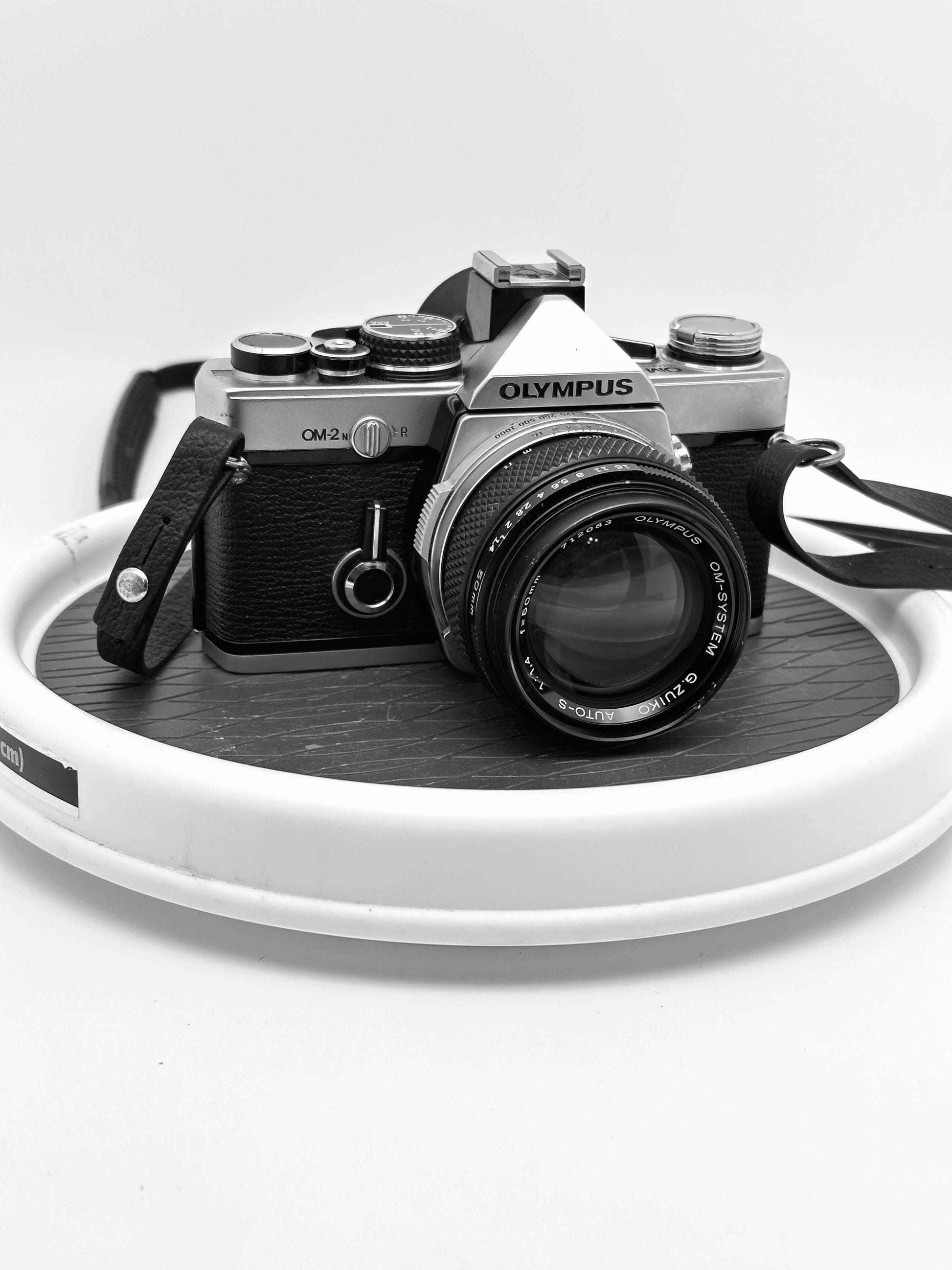 Olympus OM-2N 35mm film camera with 50mm f/1.4 lens on a display, showcasing its vintage design and character.