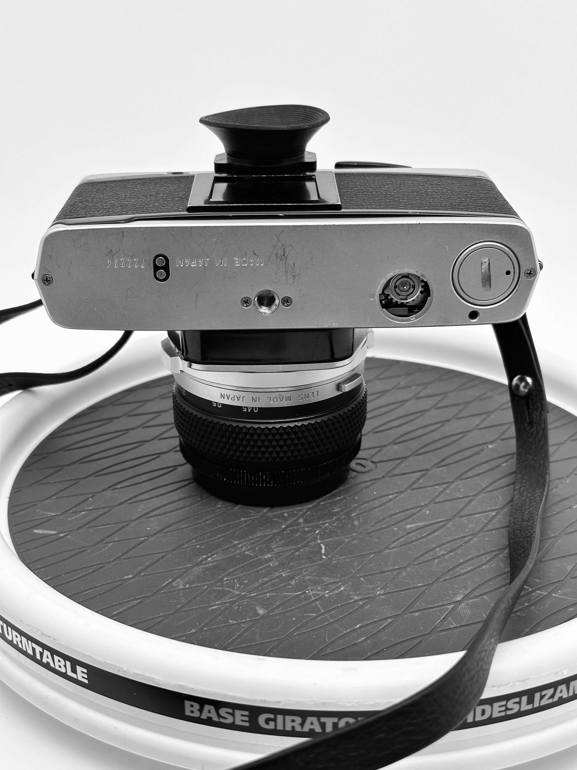 Vintage Olympus OM-2N camera with 50mm f/1.4 lens on a rotating display base.