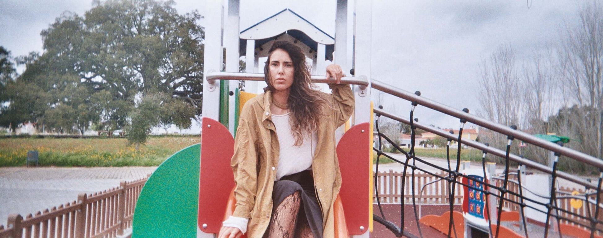 Woman sitting on a playground structure, capturing a moment in an outdoor park.