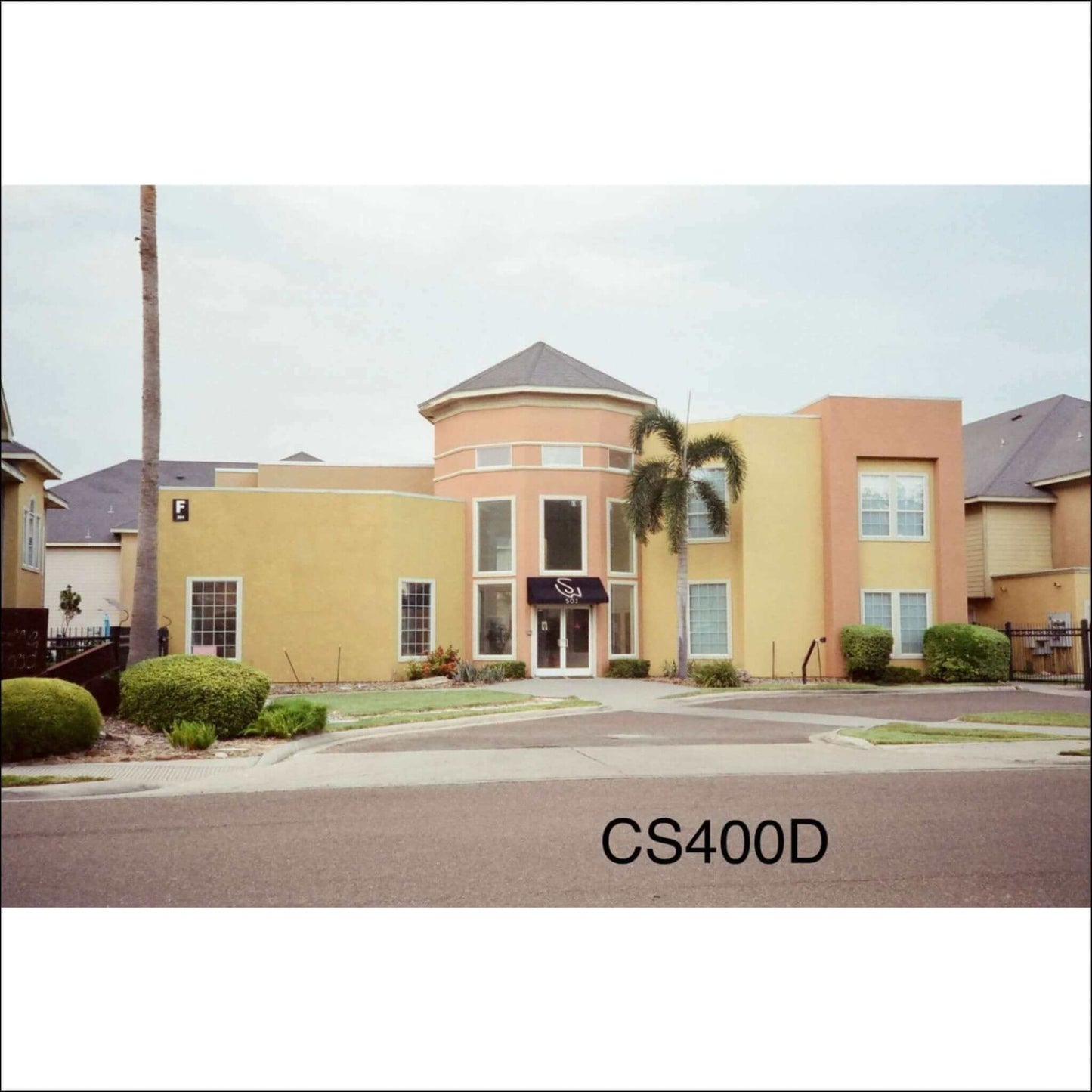 CineStill 400D film photo showing a building with vibrant yellow exterior and palm trees.