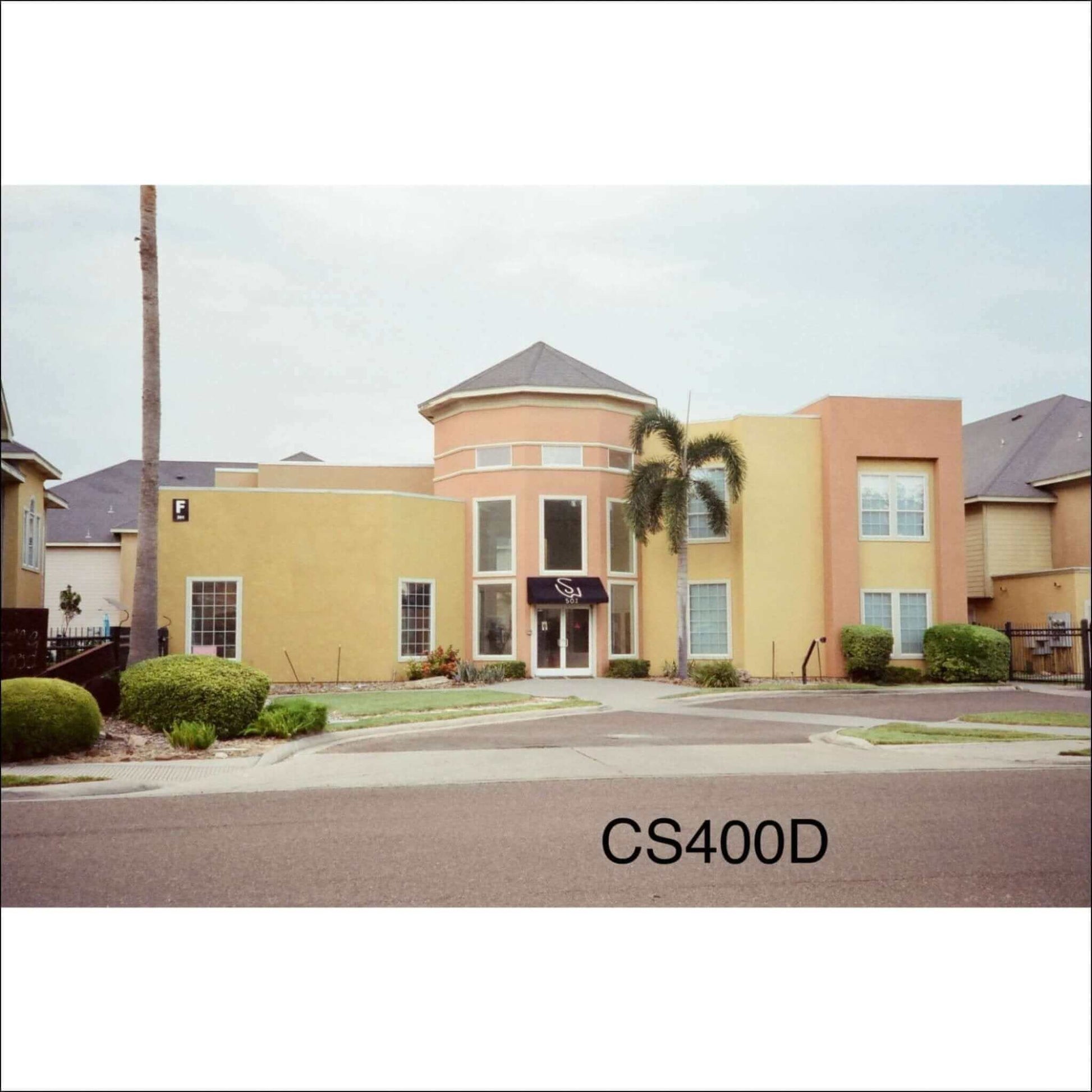 CineStill 400D film photo showing a building with vibrant yellow exterior and palm trees.