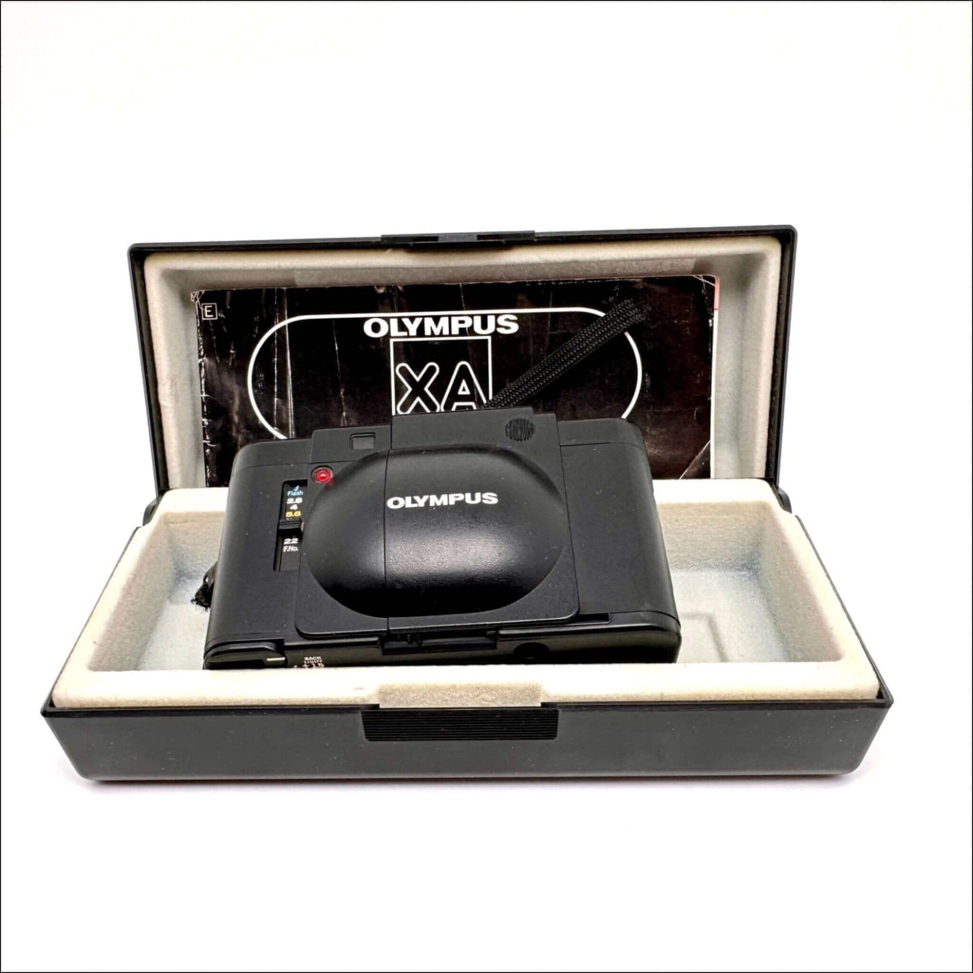 Olympus XA used 35mm vintage film camera in case with manual, showcasing its sleek design and classic features.